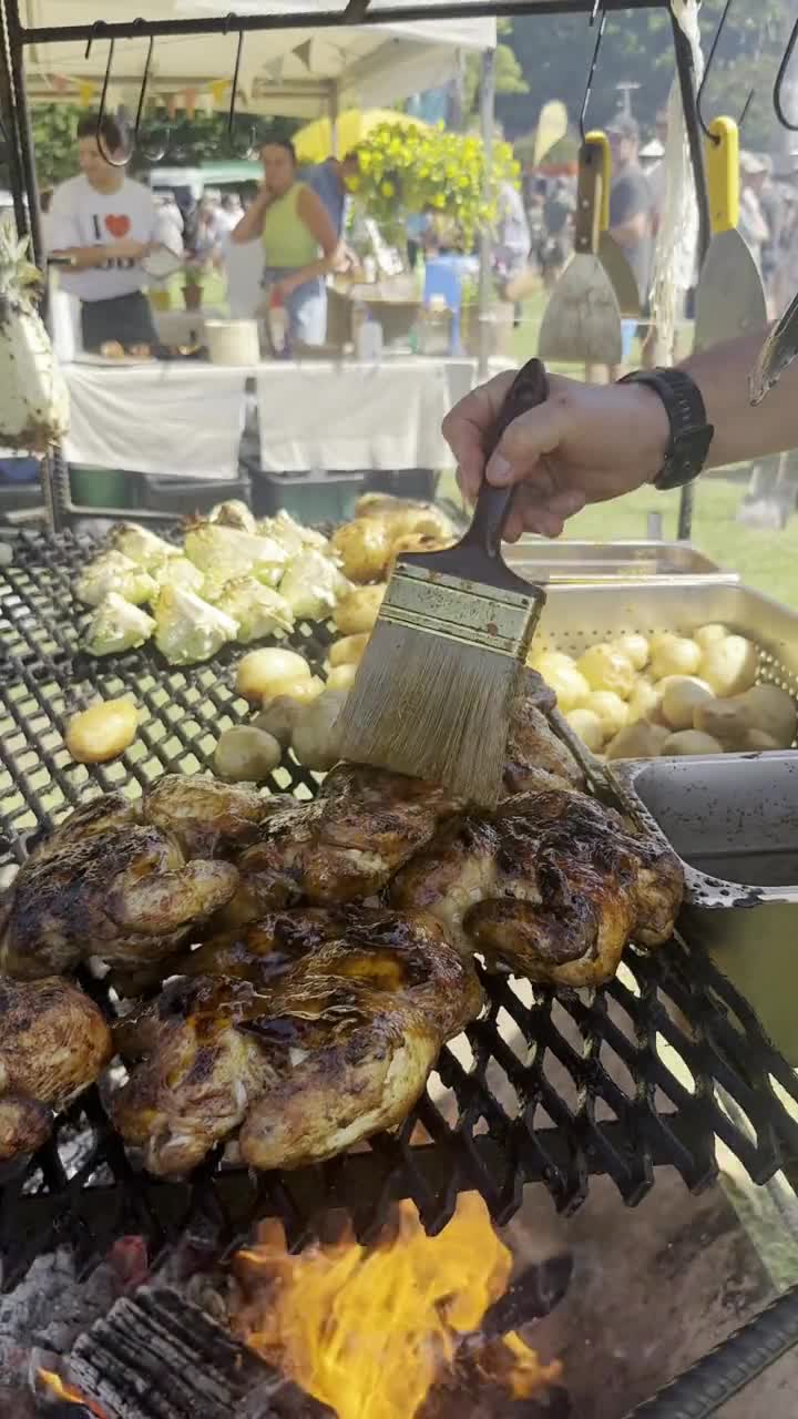 Chef basting chickens over an open fire